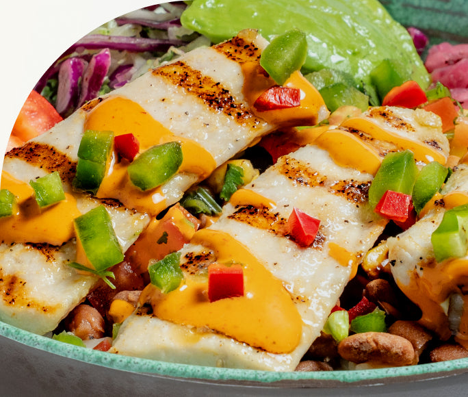 Close-up of grilled wild-caught mahi with chipotle aioli and diced peppers
